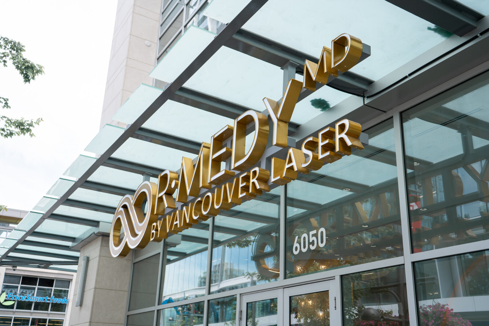Exterior view of R•Medy by Vancouver Laser clinic, featuring the clinic’s gold signage above the glass facade at 6050, enhancing its modern and professional appearance.